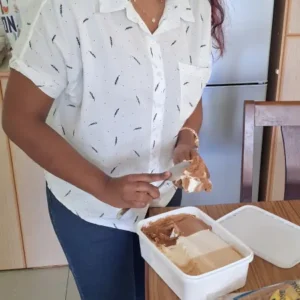 A focused volunteer prepares a scoop of ice cream during a support visit at Tamar House.