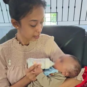 Priscilla Valayodapillai gently feeding an infant during the first support visit to Tamar House.