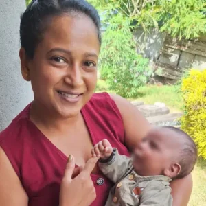 A Tamar House team member holding a baby outside, sharing a bonding moment during the charity visit.